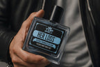 Perfume con feromonas Fastrok HERLOSS en frasco de cristal cuadrado con etiqueta azul, sostenido por una mano.